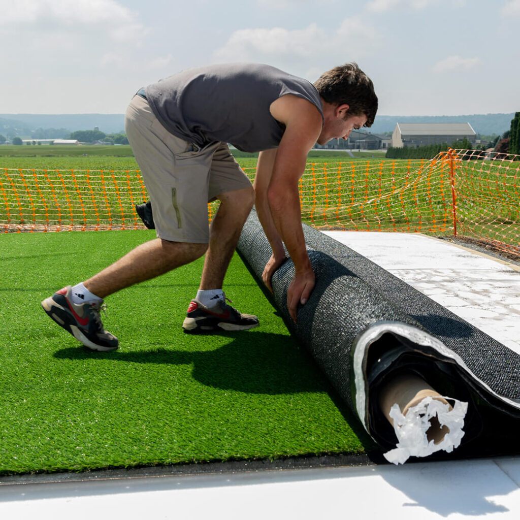 swing kingdom worker rolling out the playground surfacing