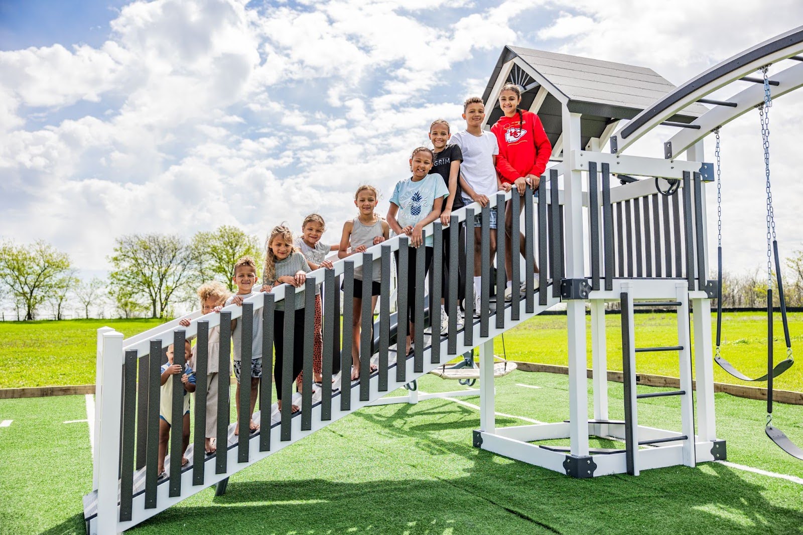 Kids standing on a sensory-rich play environment swing set.